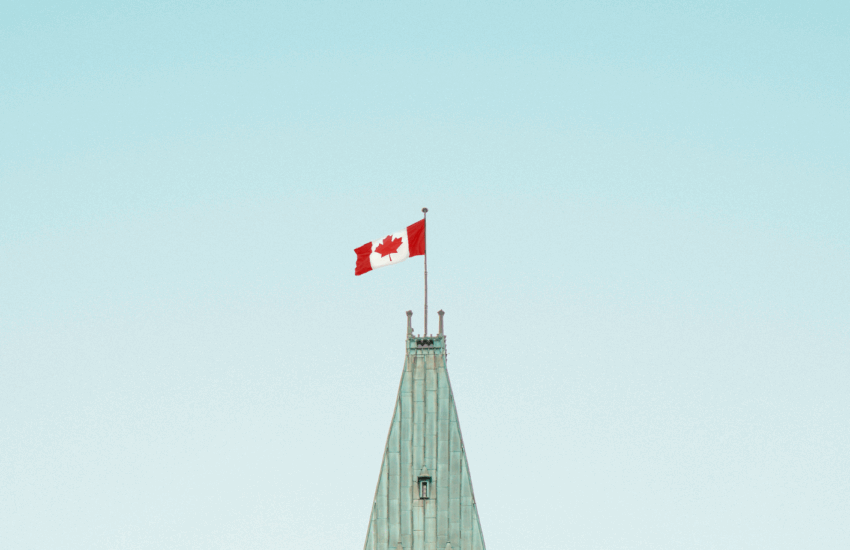 Tour de l'édifice du parlement d'Ottawa avec drapeau canadien flottant dans un ciel bleu