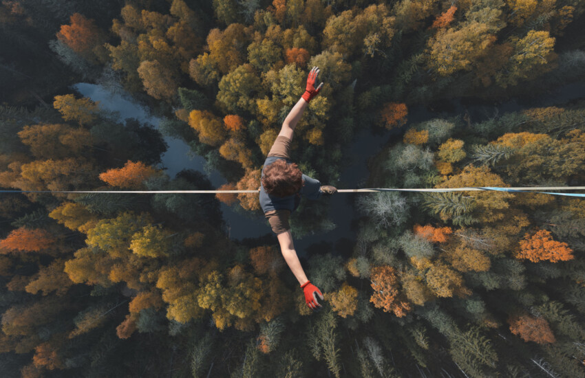 un funambuliste marche sur un fil en équilibre au dessus d'une forêt
